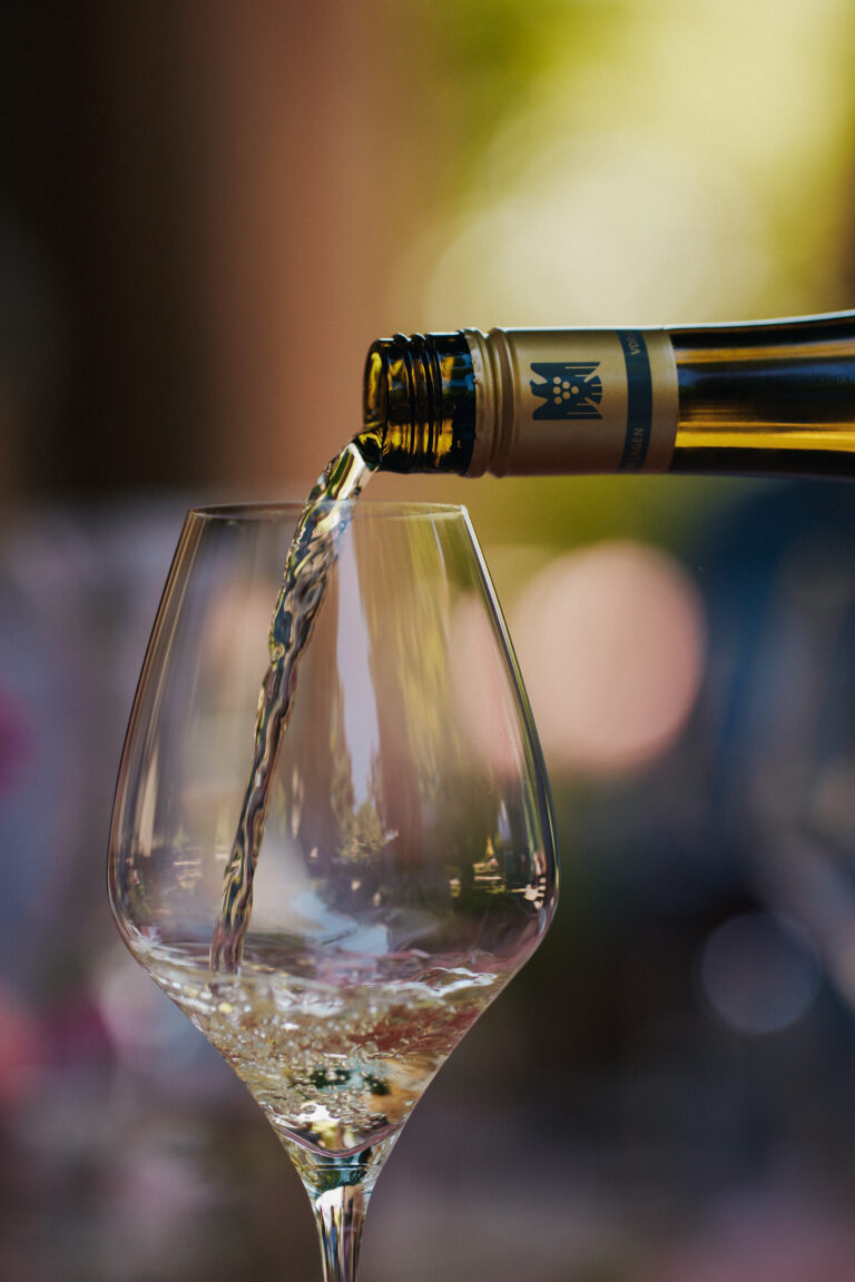Nahaufnahme zeigt den Einschank von Weißwein aus einer Knipserflasche in ein Glas